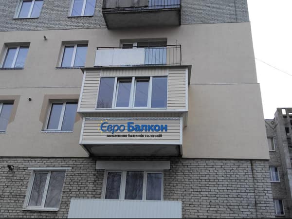 Балкон із бежевим сайдингом та металопластиковим засклення