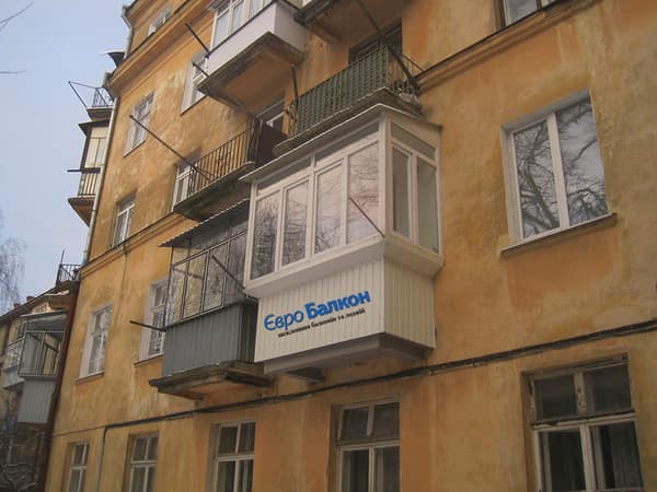 Засклений балкон у будинку старої забудови Львова з вивіскою ЄвроБалкон